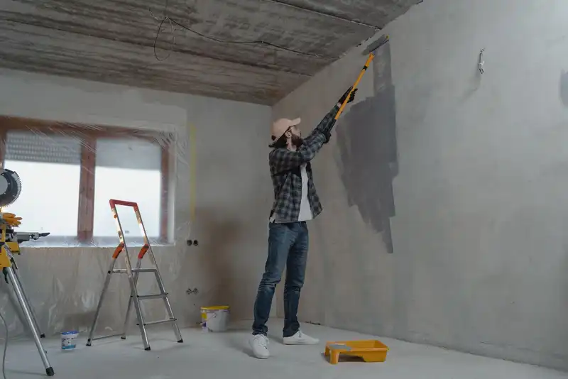 Pintor profesional aplicando pintura en una pared con rodillo en una vivienda de Lorca